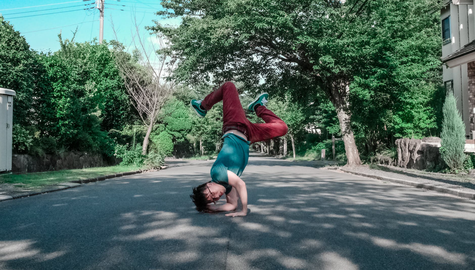 man doing head stand on road